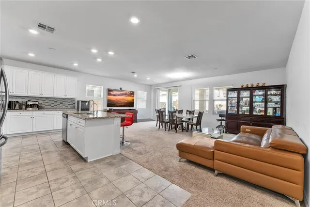 a kitchen with stainless steel appliances granite countertop a stove a sink a refrigerator and white cabinets with wooden floor