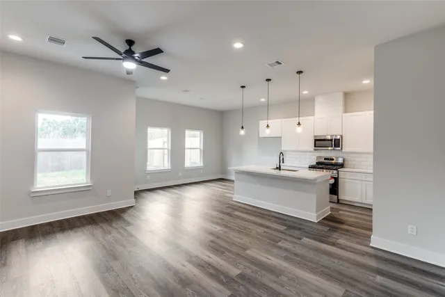 a living room with stainless steel appliances kitchen island hardwood floor and a window
