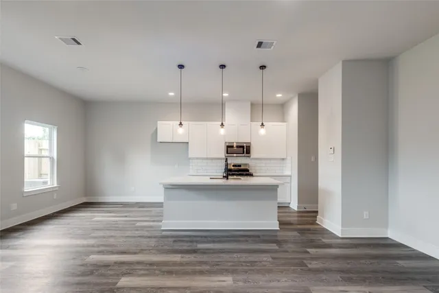 a view of a kitchen with kitchen island a sink wooden floor and a living room view