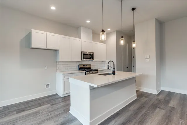 a kitchen with a sink a counter top space stainless steel appliances and cabinets