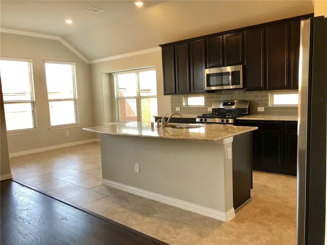 a kitchen with stainless steel appliances granite countertop a stove a sink and a microwave