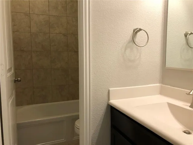a bathroom with a granite countertop sink a toilet and shower