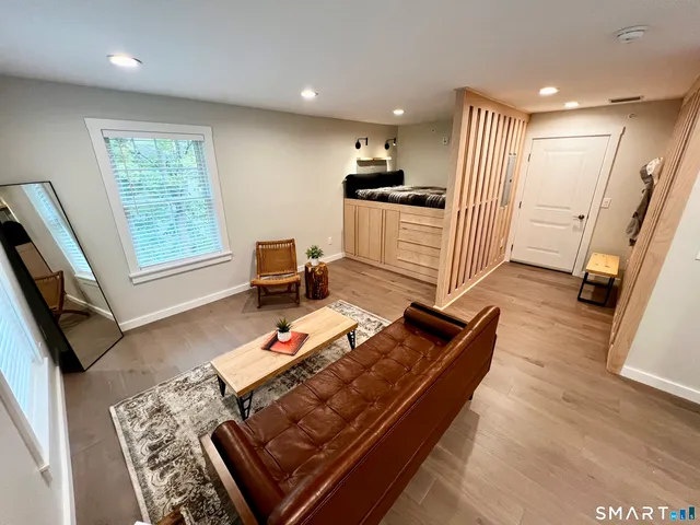a living room with stainless steel appliances furniture and a wooden floor