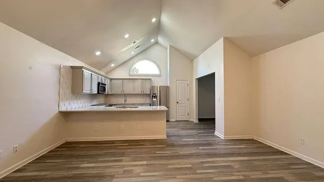 a view of a kitchen with a sink and dishwasher a refrigerator with wooden floor
