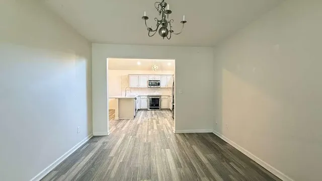 a view of a room with wooden floor staircase and a kitchen space