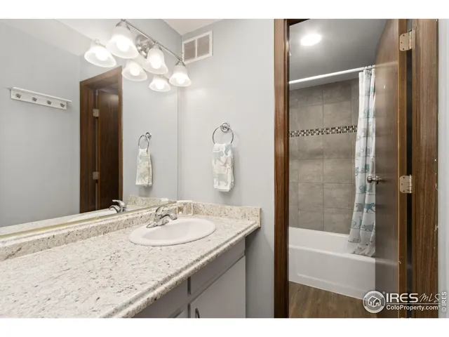 a bathroom with a granite countertop sink a mirror and a shower