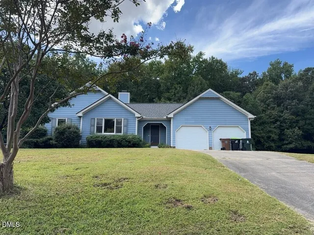 a front view of house with yard and trees in the background