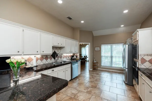 a kitchen with granite countertop a stove a sink and a refrigerator