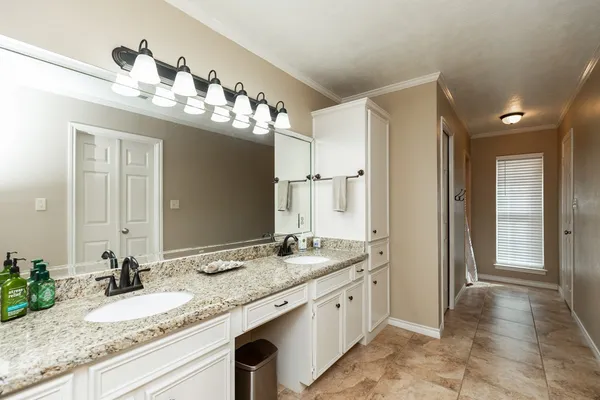 a bathroom with a granite countertop double vanity sink and a mirror