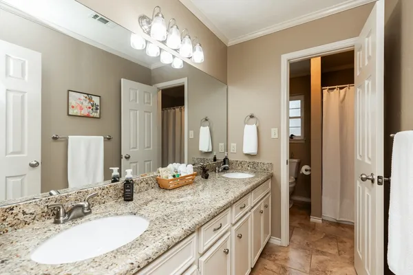 a bathroom with a granite countertop double vanity sink and a mirror
