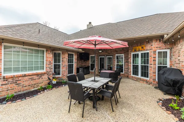 a patio with a table and chairs and potted plants