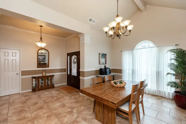 a dining room with wooden floor a chandelier a wooden table and chairs