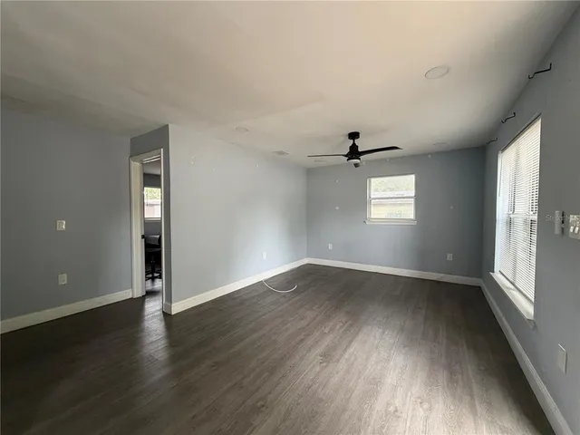 an empty room with wooden floor cabinet and windows