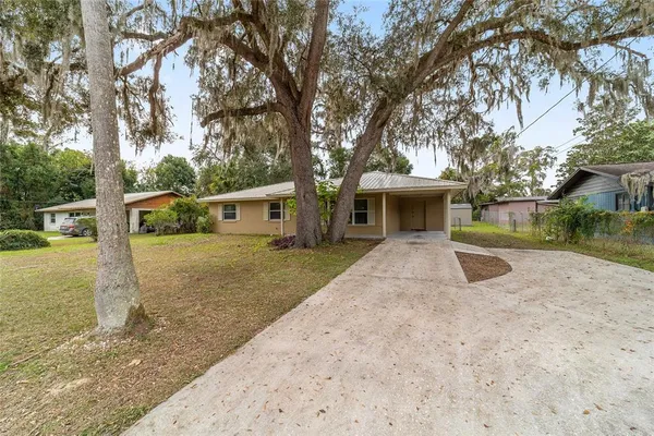 a view of a house with a yard and large tree