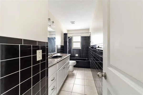 a bathroom with a granite countertop sink a toilet a mirror and shower
