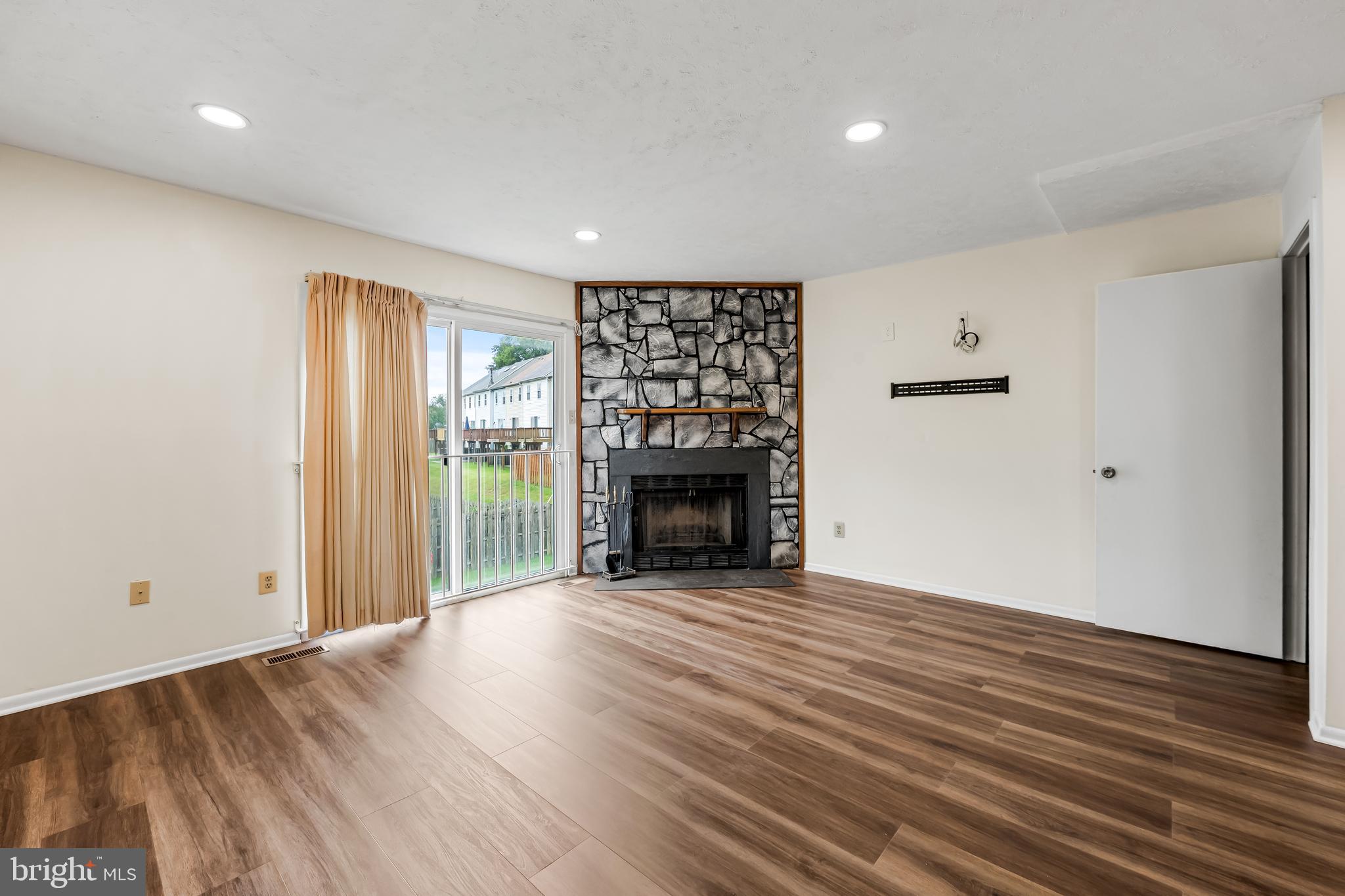 6953 Rockfield Road Baltimore, MD 21244 - Photo 3 of 31 an empty room with wooden floor fireplace and windows