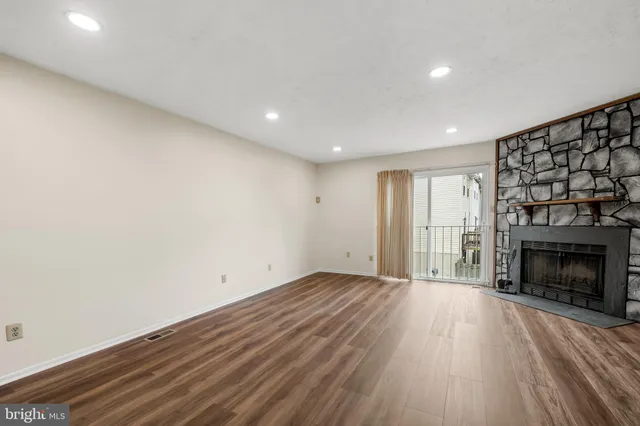 an empty room with wooden floor fireplace and windows