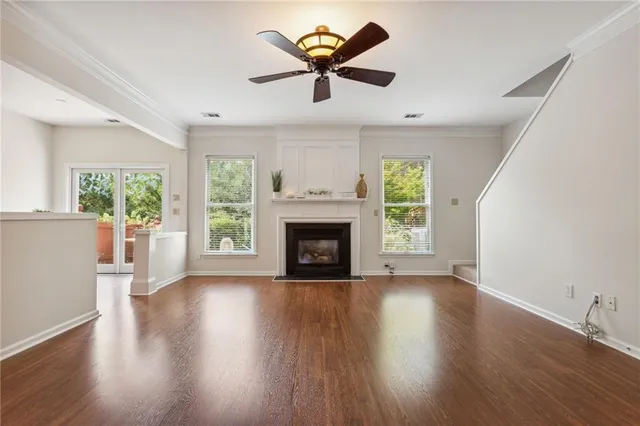 an empty room with windows a fireplace and a chandelier fan