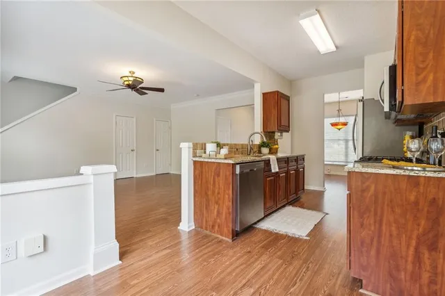 a kitchen with stainless steel appliances granite countertop a stove a sink dishwasher and a refrigerator with wooden floor