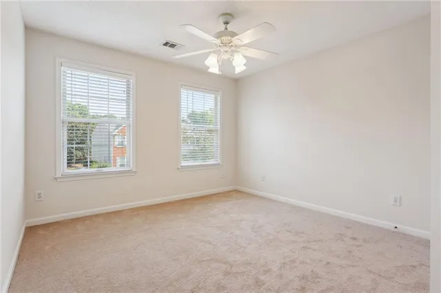 an empty room with windows and chandelier fan