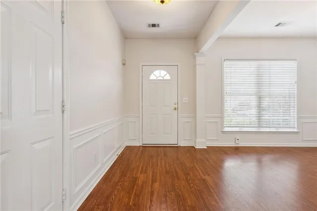 an empty room with wooden floor and windows