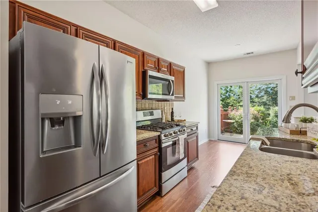 a kitchen with stainless steel appliances granite countertop a refrigerator stove and sink