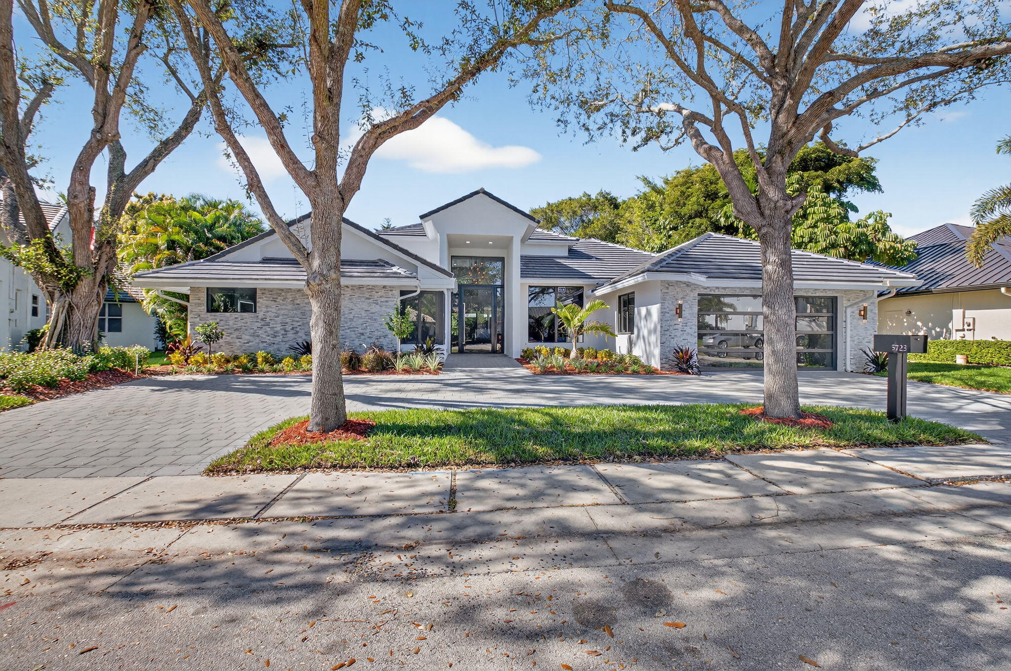 a front view of a house with a yard and large tree