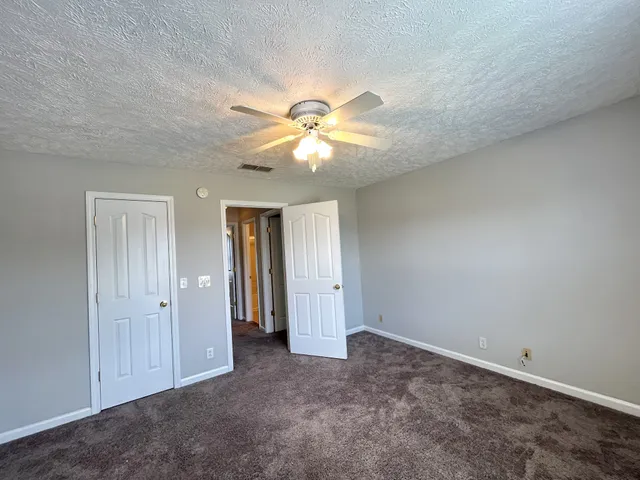 an empty room with closet and a ceiling fan