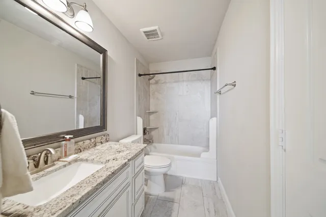 a bathroom with a granite countertop sink toilet and shower