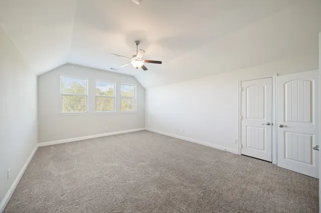 an empty room with windows and ceiling fan