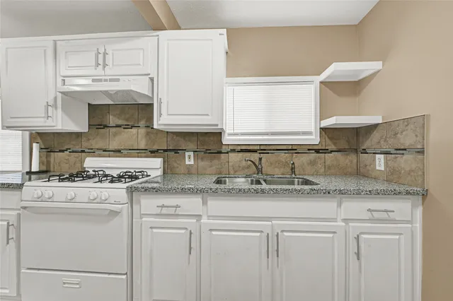 a kitchen with granite countertop white cabinets and white appliances
