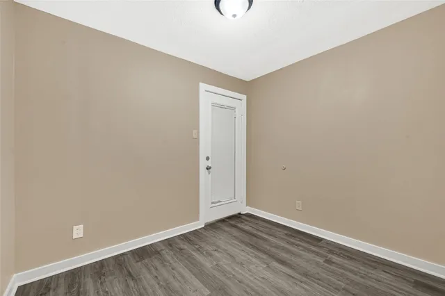 a view of an empty room with wooden floor and closet