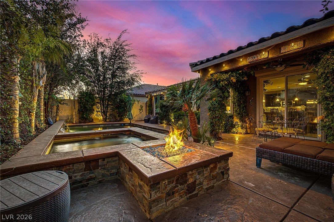 7415 Campbell Ranch Avenue Las Vegas, NV 89179 - Photo 47 of 52 An inviting backyard oasis beckons with a sparkling pool and a cozy fire pit under a vibrant sunset.