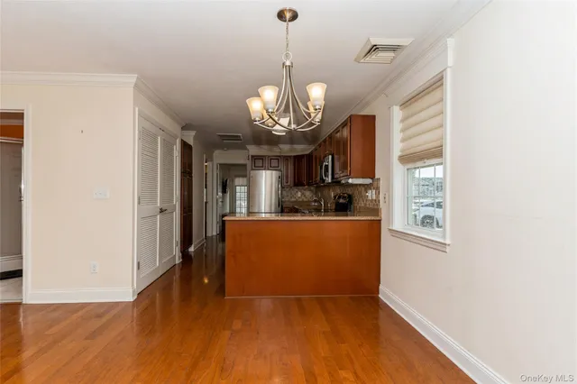 an empty room with wooden floor chandelier and windows