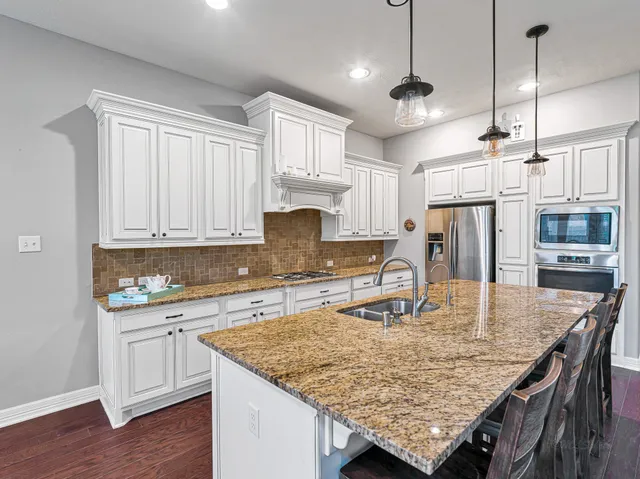 a large kitchen with kitchen island a large counter space a sink stainless steel appliances and cabinets