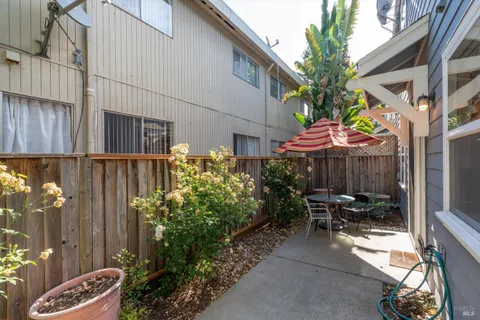 a view of a patio with table and chairs and potted plants with wooden fence