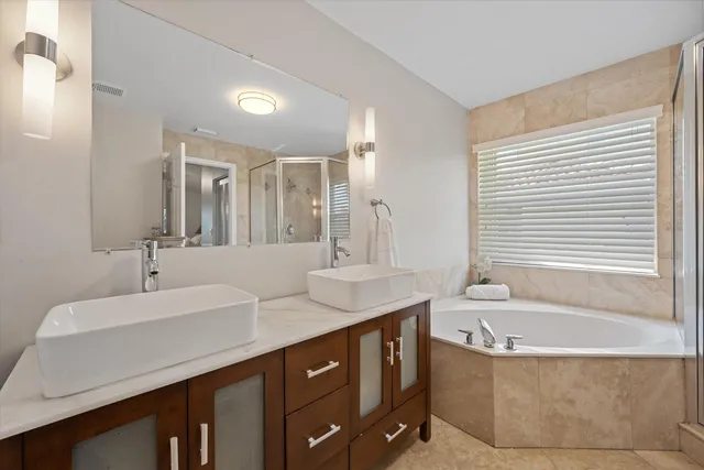 a bathroom with a bathtub a double vanity sink and mirror