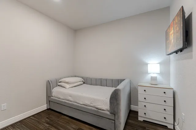 a bedroom with a bed and flat tv screen on the dresser