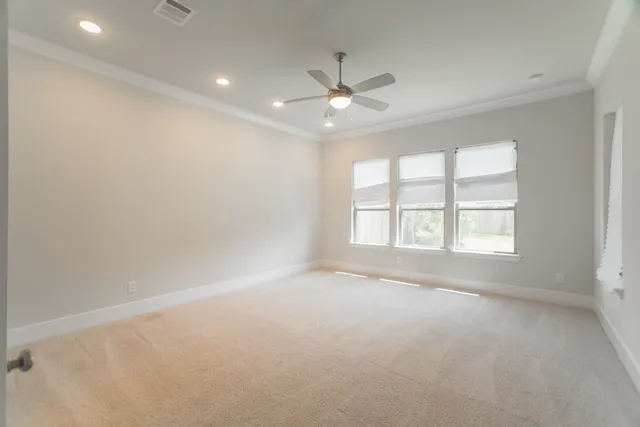 an empty room with a ceiling fan and windows