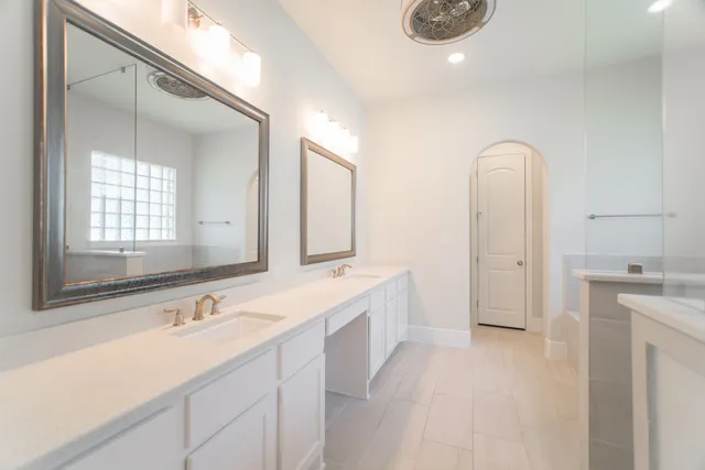 a spacious bathroom with a double vanity sink a mirror and a bathtub