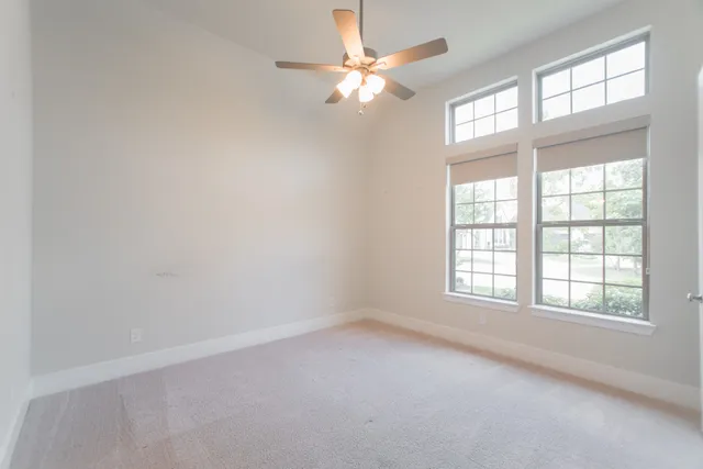 an empty room with a window and a ceiling fan