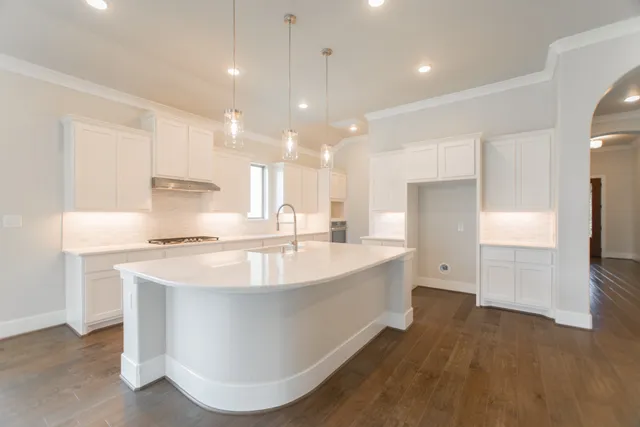 a large kitchen with stainless steel appliances a large counter top a stove and a refrigerator