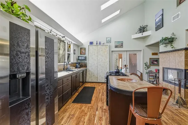 a kitchen with stainless steel appliances granite countertop a refrigerator a stove a sink dishwasher and white cabinets with wooden floor