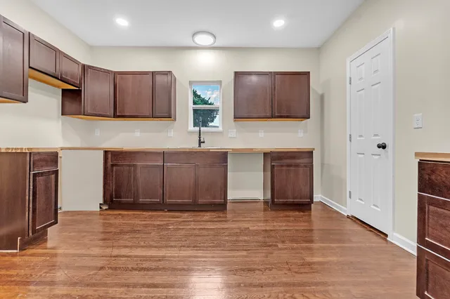 a kitchen with cabinets wooden floor and stainless steel appliances