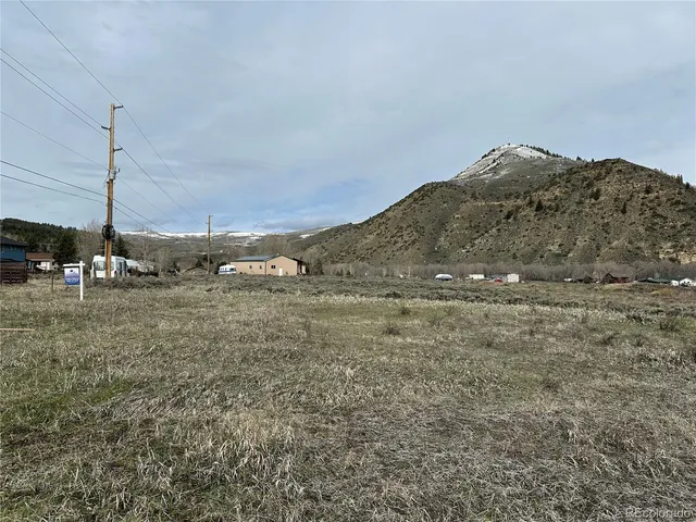 a view of a dry field with trees in background