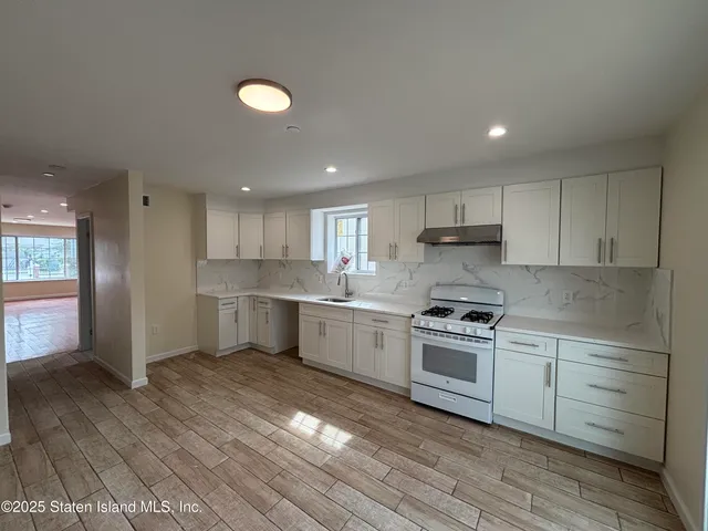 a kitchen with a white cabinets stove and wooden floor