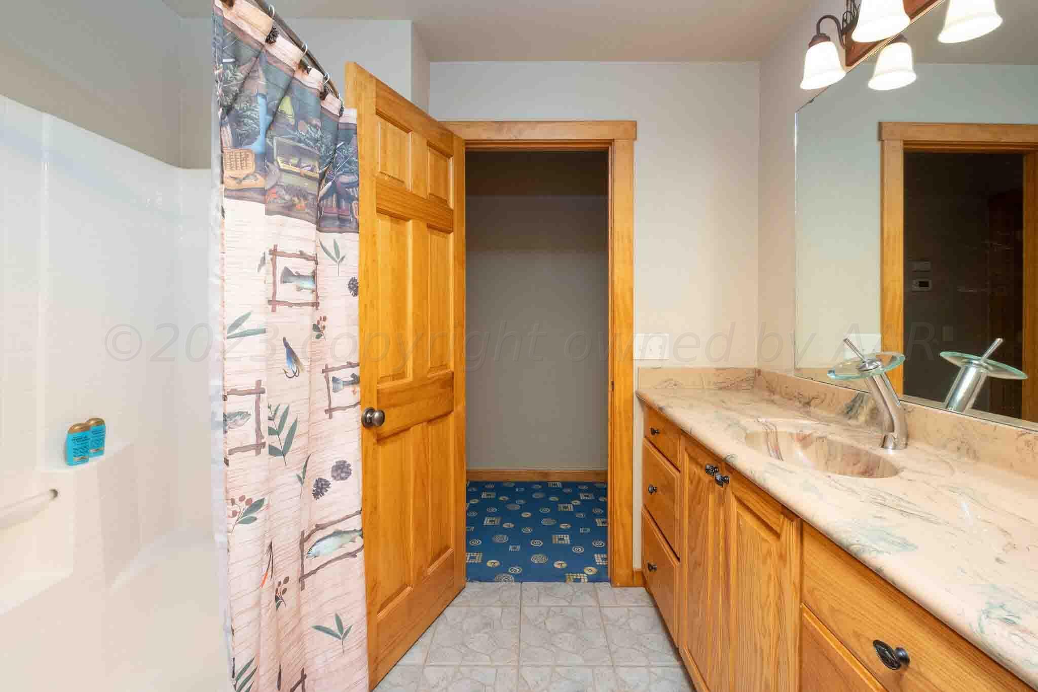 21401 Hope Road Canyon, TX 79015 - Photo 51 of 121 a bathroom with a granite countertop sink a mirror a vanity and a shower