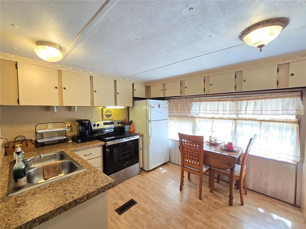 1621 Haddock Street St. Cloud, FL 34771 - Photo 25 of 46 a kitchen with stainless steel appliances granite countertop a stove top oven a sink dishwasher a dining table and chairs with wooden floor