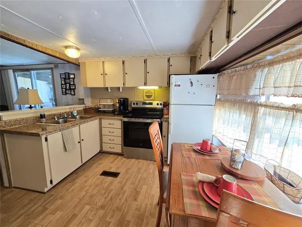a kitchen with stainless steel appliances kitchen island wooden floors stove and white cabinets