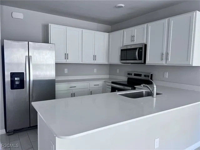 a kitchen with stainless steel appliances a refrigerator sink and microwave